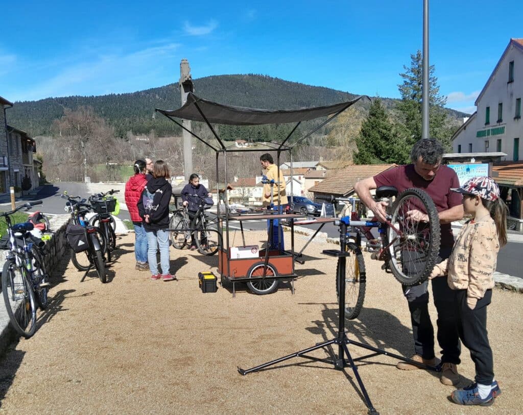 Un atelier vélo déployé autour de la remorque vélo sur la place de Vollore-Montagne.